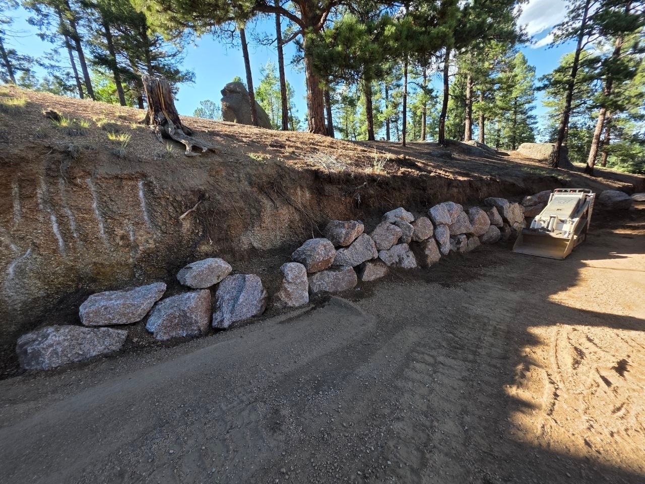 Driveway boulder wall under construction with Bobcat for scale — Oakden Enterprises